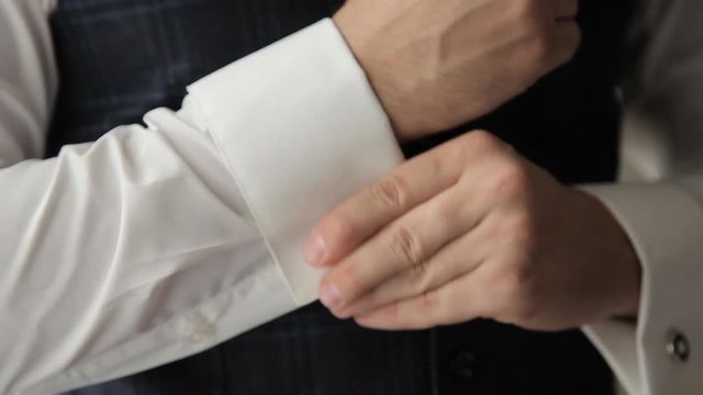 zips the cufflink on his shirt sleeve