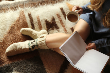 Beautiful woman drinking hot cacao and reading book at home