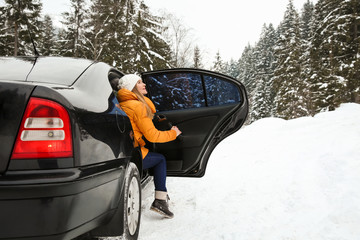 Young woman getting out of car at snowy winter resort