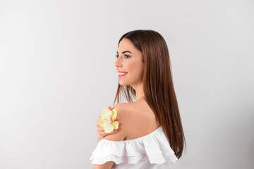 Beautiful young woman with orchid flower on white background