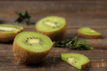 Delicious ripe many kiwi fruit and kiwi in a cut on a brown wooden table. close-up.
