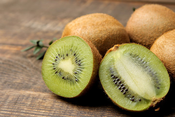 Delicious ripe many kiwi fruit and kiwi in a cut on a brown wooden table. close-up.