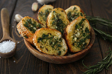 Bowl with tasty cut garlic bread on wooden table