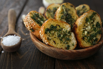 Bowl with tasty cut garlic bread on wooden table