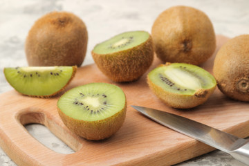 Delicious ripe lots of kiwi fruit and kiwi cut on a board on a light concrete background.