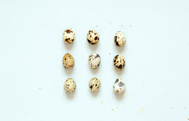 Pattern with quail eggs and golden glitter on blue background.