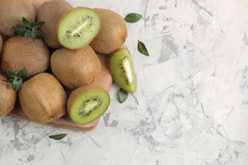 Delicious ripe lots of kiwi fruit and kiwi cut on a board on a light concrete background. top view. space for text