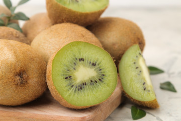 Delicious ripe lots of kiwi fruit and kiwi cut on a board on a light concrete background. close-up .
