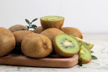 Delicious ripe lots of kiwi fruit and kiwi cut on a board on a light concrete background.