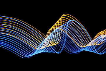 Long exposure, light painting photography.  Blue and metallic gold abstract design of swirls and waves, vibrant color against a black background