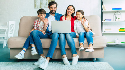 Happy beautiful family with laptop on the couch at home in casual clothes