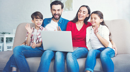 Happy beautiful family with laptop on the couch at home in casual clothes