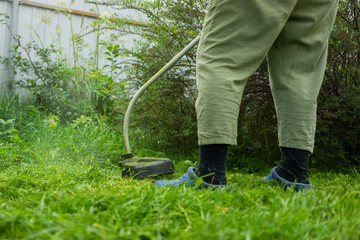 Woman is trimming her lawn with electric edge trimmer