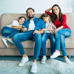 Beautiful happy family watch TV on the couch at home and smiling