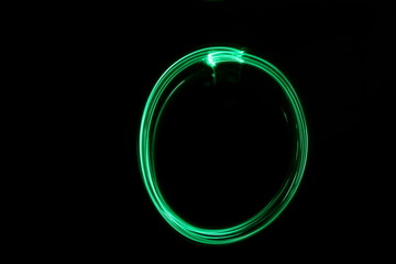 Long exposure, light painting photography.  Abstract circle outline design, vibrant green color against a black background