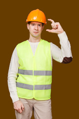 the man in a construction helmet, a vest, shows fingers big and index the size