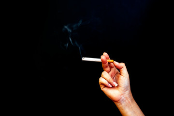 Image of cigarette in hand with smoke on black background