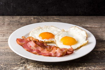Fried eggs and bacon for breakfast on wooden table. 
