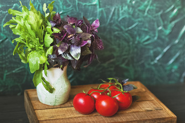 The natural texture of ripe juicy farm vegetables close-up and copy space. Tomatoes, greens, basil, onion, dill, parsley, garlic on a dark background, the concept of healthy food, toned photo