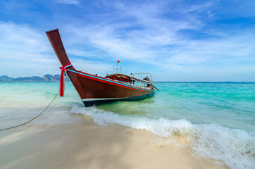 Fototapeta premium Wooden boat parked on the sea, white beach on a clear blue sky, blue sea
