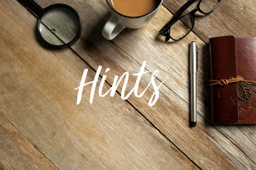 Top view of a cup of coffee,magnifying glass,glasses,pen and notebook on wooden background written...