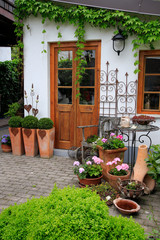Gartendekoration mit Blühpflanzen am Haus