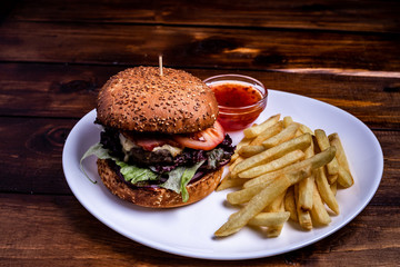 Beefburger with fried sweet potatoes served on a white plate