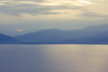 abstract mountain ridge silhouette near big lake natural water reservoir landscape background wallpaper pattern photography in foggy morning weather time 