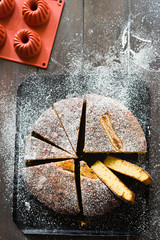 Banana cake made with almond and gluten free, shot from a top viewpoint over a rusty wooden balck background
