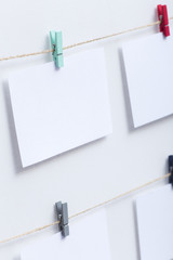 blank white cards hanging on colored clothespins on a thread on a white background, a template for a photo collage, a concept of memories and a photo industry