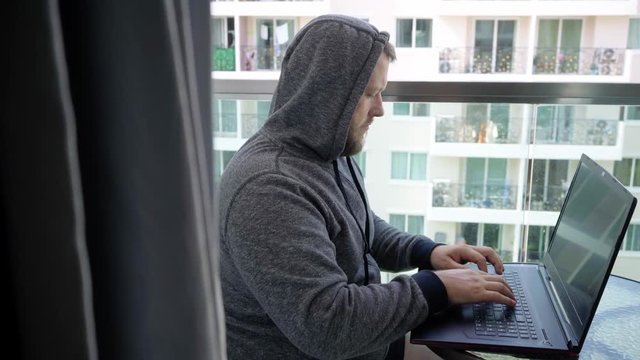 Cybercrime, hacking and technology concept - male hacker writing code or using computer virus program for cyber attack