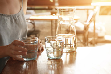 Woman with glass of water at table indoors