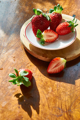 Fresh Strawberry in a plate on a wooden table background