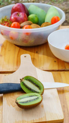 White knife with kiwi and tomato fruits on wooden floor