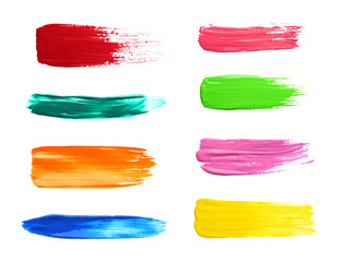 Set with abstract brushstrokes of different bright paints on white background, top view