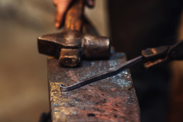 blacksmith makes an artistic forging of hot metal on the anvil.