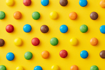 Colorful candy pattern on a yellow background viewed from above. Sweet bonbons repetition design isolated on a yellow background. Top view