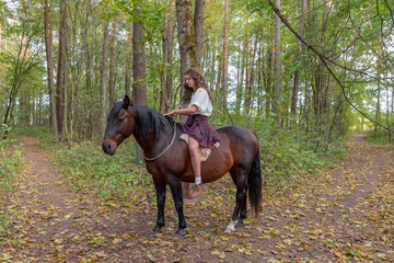 Girl in a Scottish kilt on a horse, holding a sword in her hand