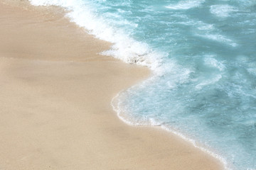 Beautiful blue wave with sea foam on sandy beach