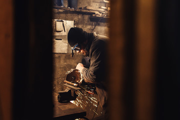 worker in the workshop cuts a metal blank a grinder.