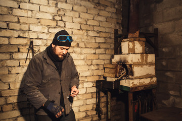 Fototapeta premium bearded blacksmith fires fire with firesteel and flint.
