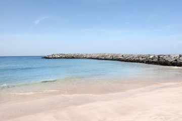 Fototapeta na wymiar Picturesque view of beautiful beach with stone breakwater on sunny day