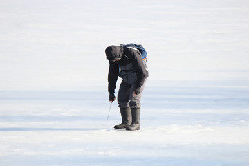 Fototapeta na wymiar fisherman measures the thickness of the ice