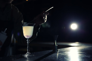 Barman adding cranberry syrup into cosmopolitan martini cocktail at counter, closeup. Space for text