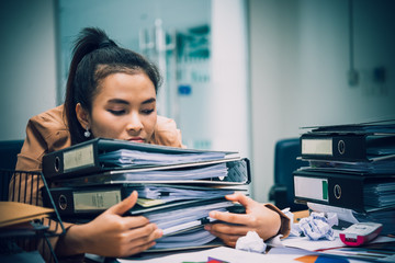 Asian woman working in office,young business woman stressed from work overload with a lot file on...