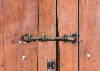 Old locked padlock rusty on the gate wooden door plank brown background.