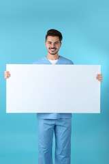 Medical student with blank poster on color background. Space for text