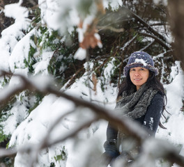 Asian woman standing in trees with snow on her hat