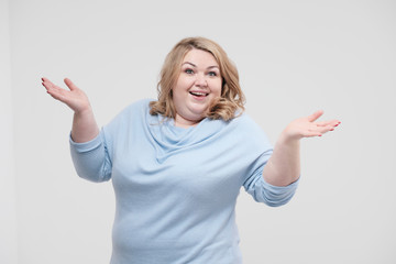 Fototapeta na wymiar Young obese woman in casual blue clothes on a white background in the studio. Bodypositive.