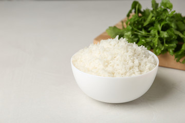Bowl of boiled rice on light table. Space for text
